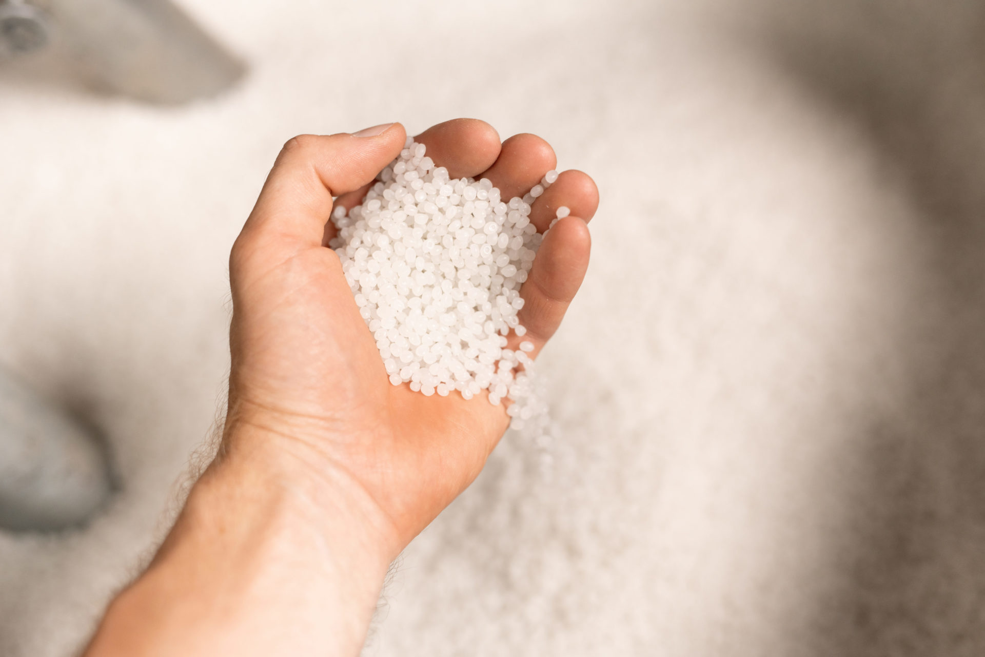 Close up of a hand holding polymer granules