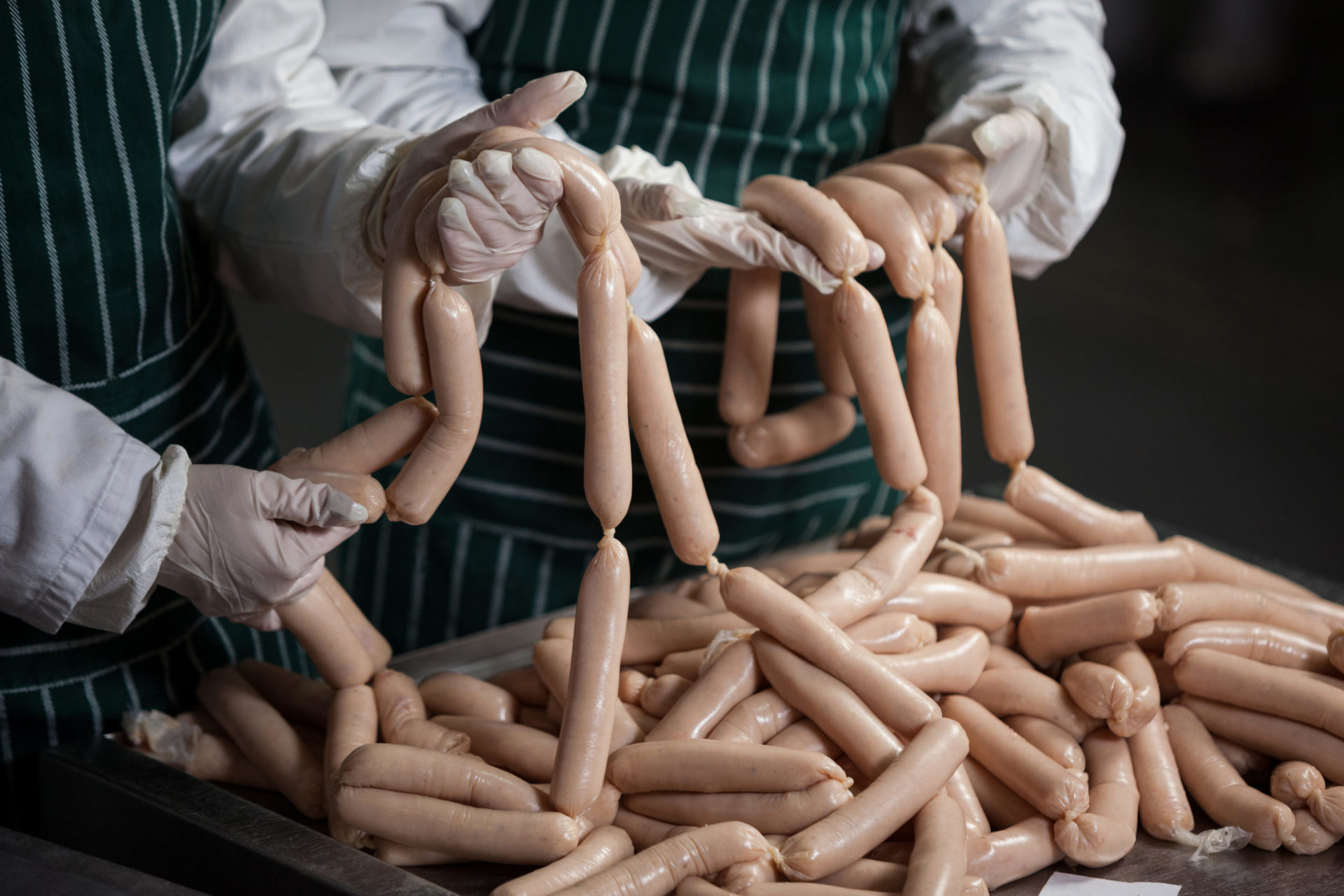 Sausages that have been produced in a butcher's shop and are checked by two employees