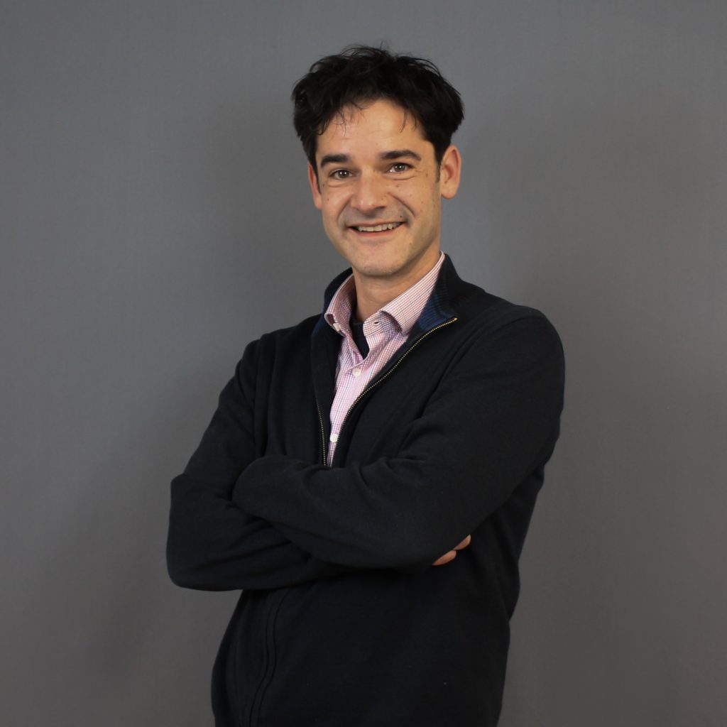 Ein Portrait von Karsten Wabnitz vor einem grauen Hintergrund mit quadratischen Maßen